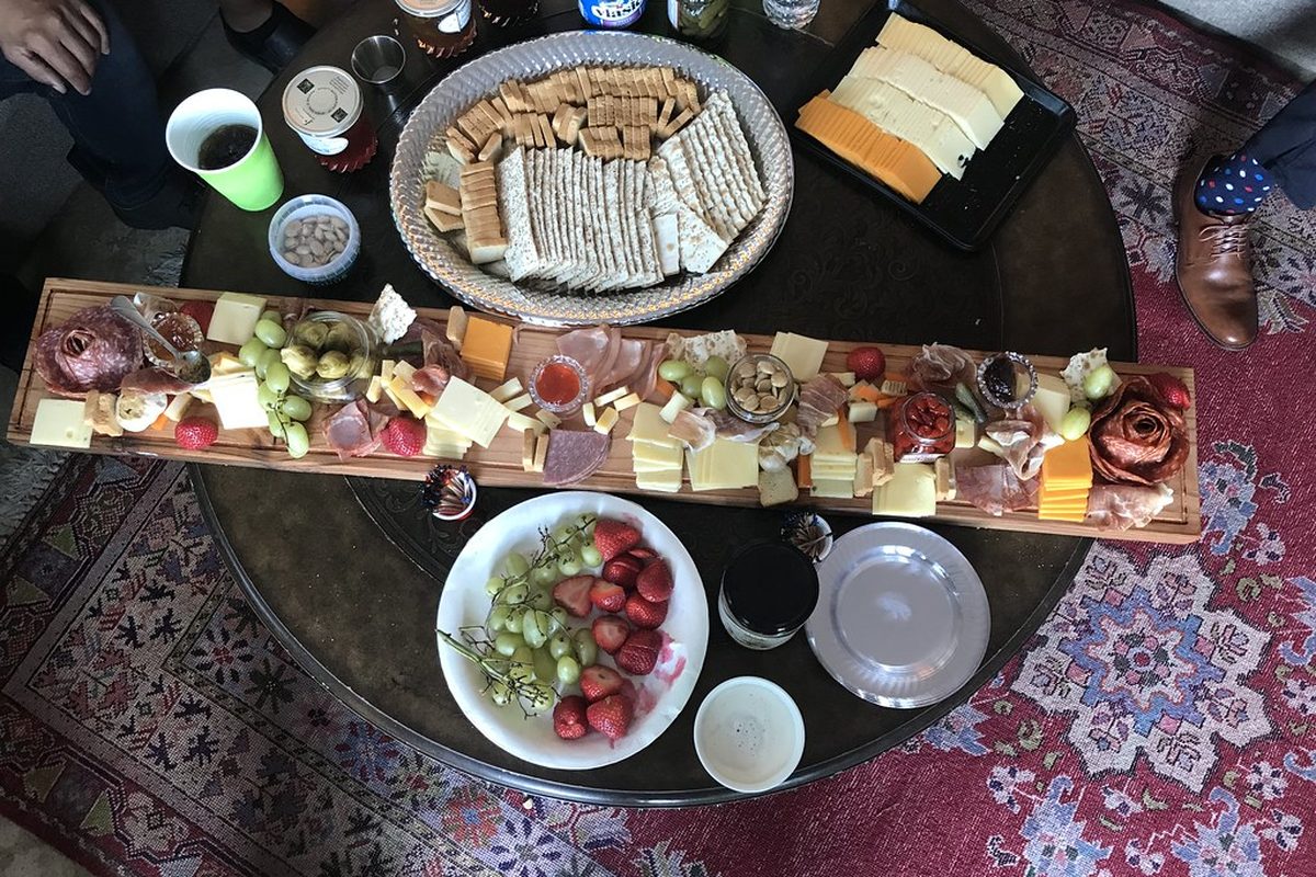 A glass of red wine next to a board of aged cheeses.
