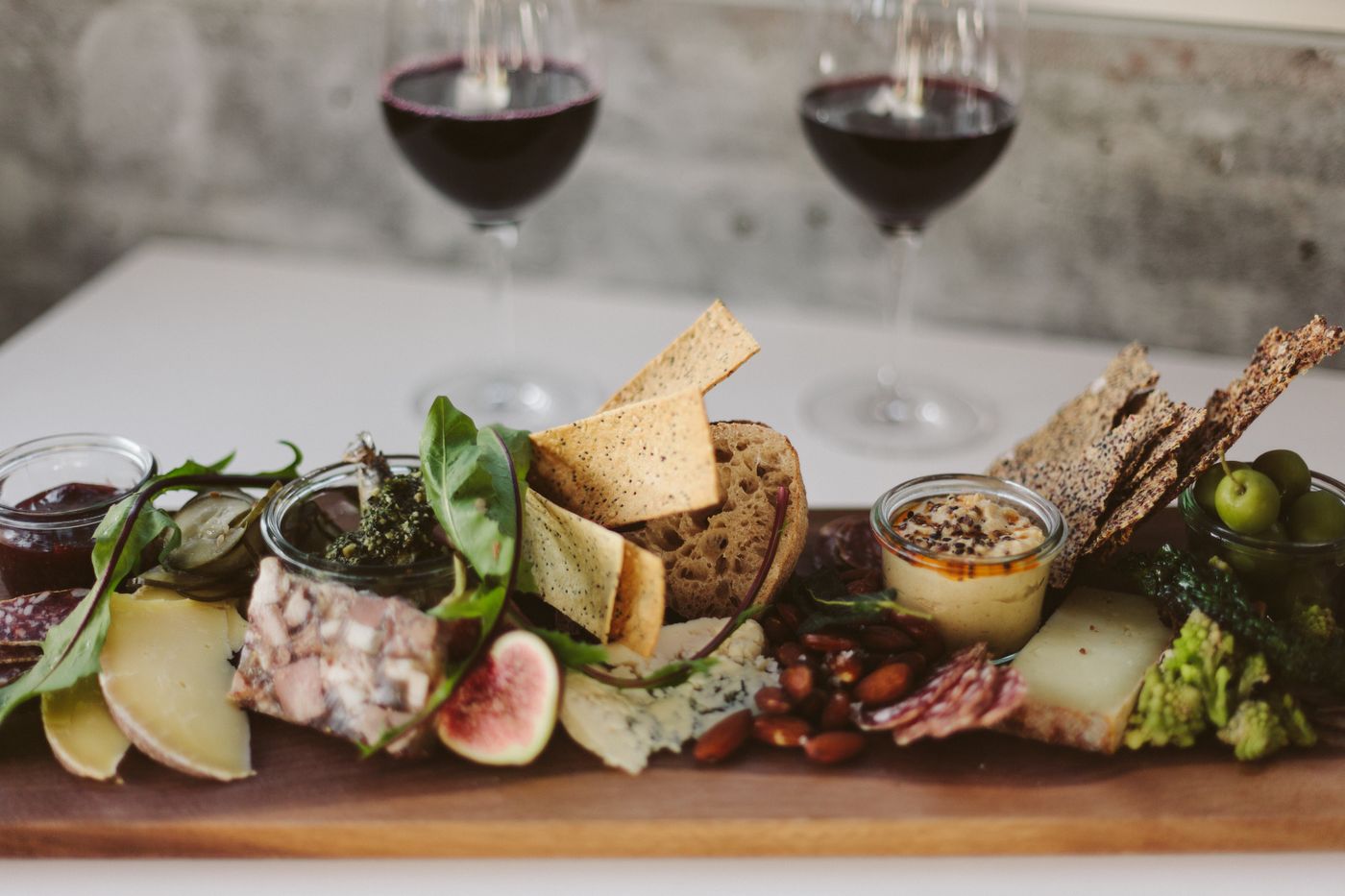 A glass of red wine next to a board of aged cheeses.