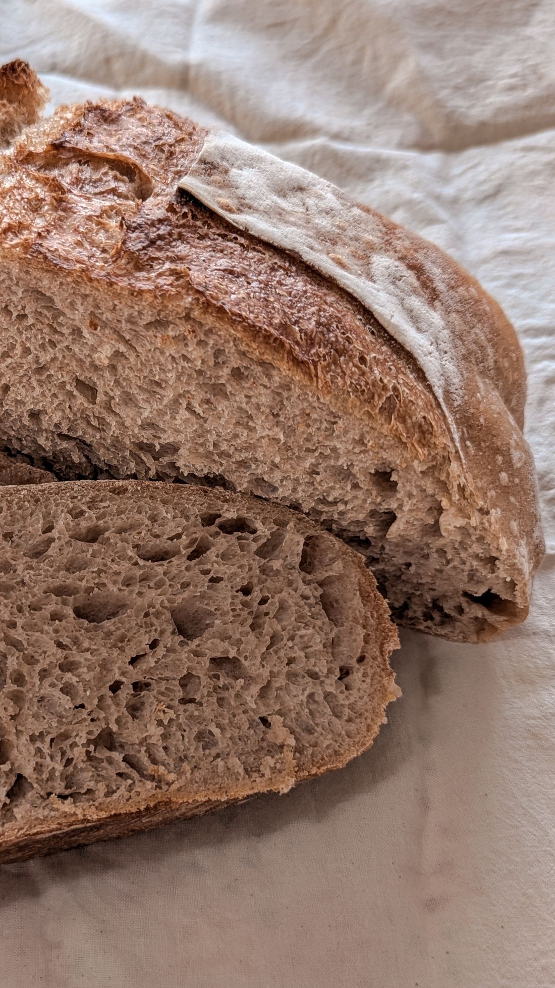 A sliced loaf of crusty sourdough bread on a board.